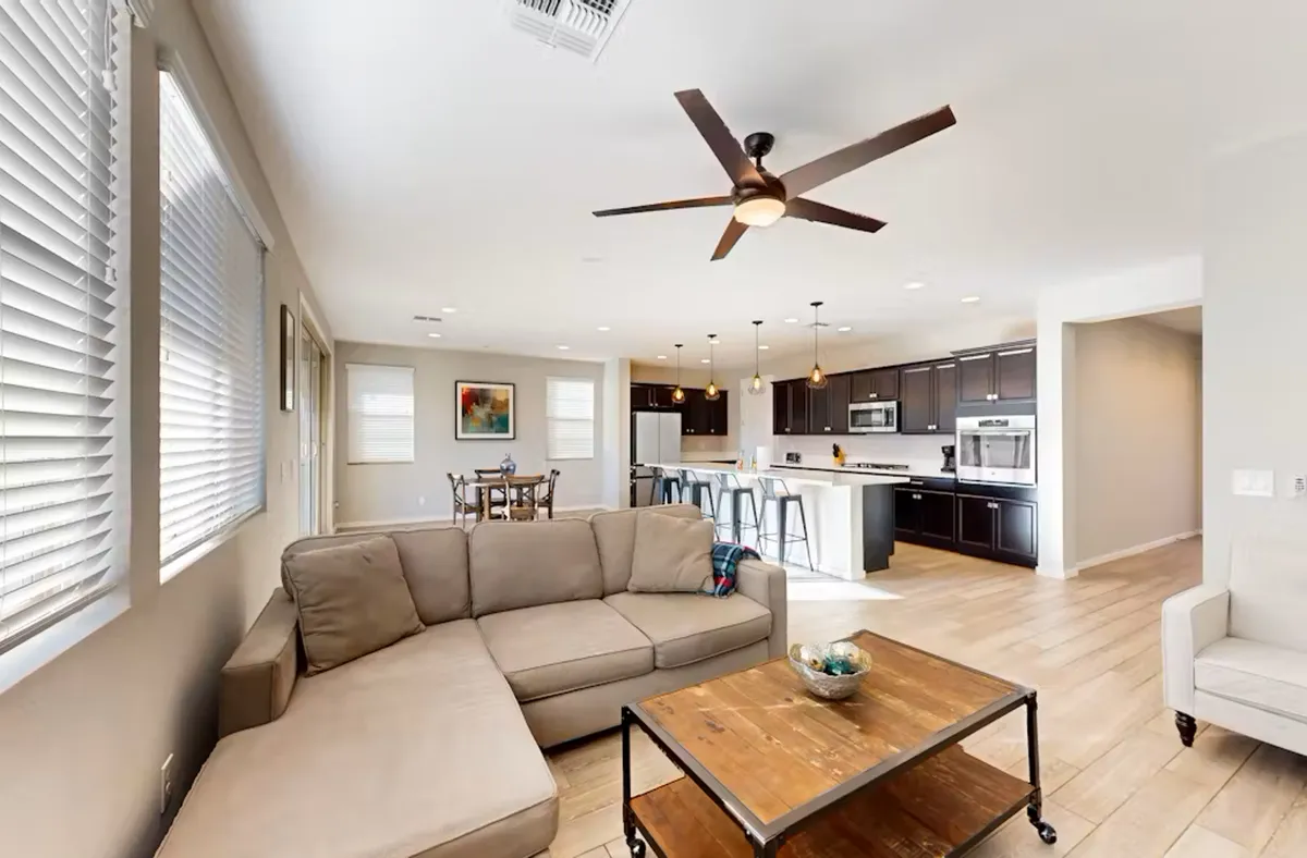 A cozy, well-appointed living room featuring a plush sofa and coffee table, seamlessly flowing into the kitchen and dining area. The space is styled for both relaxation and lively gatherings, inviting both quiet nights and vibrant celebrations.